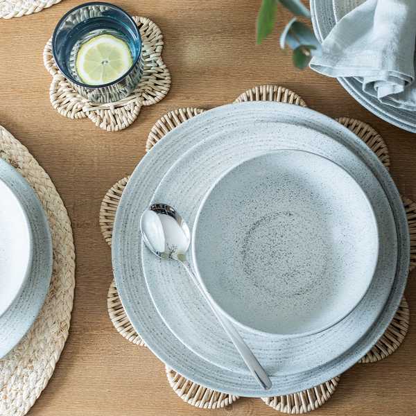 A spring dining table set up with stone effect tableware and wicker scalloped placemats.